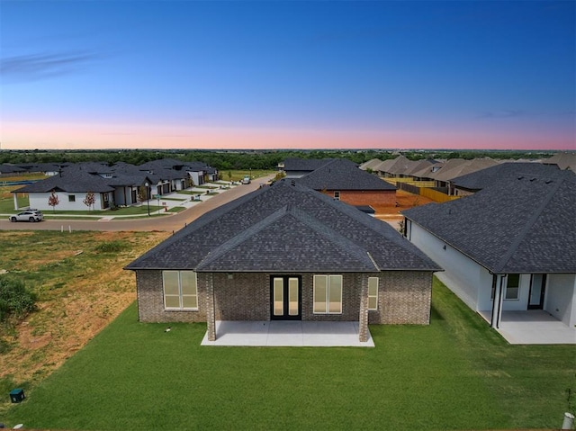 15600 Rockwell Park Ln, Edmond, OK 73013 - back of property featuring a patio area, a residential view, a lawn, a shingled roof, and brick siding