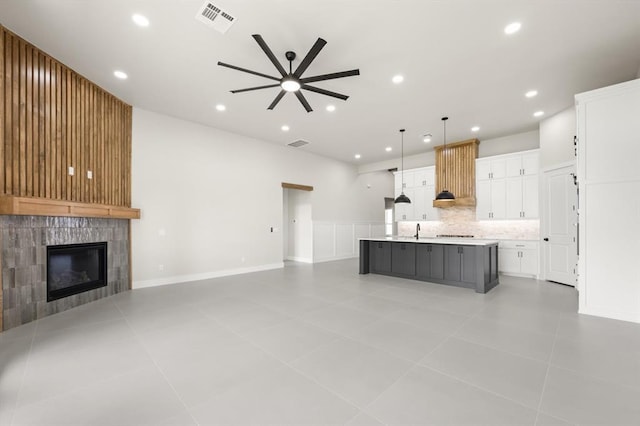 15600 Rockwell Park Ln, Edmond, OK 73013 - kitchen featuring a ceiling fan, open floor plan, a tile fireplace, white cabinetry, and recessed lighting