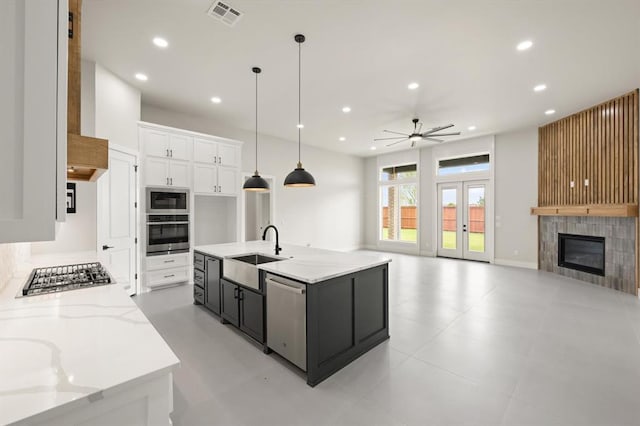 15600 Rockwell Park Ln, Edmond, OK 73013 - kitchen with stainless steel appliances, a ceiling fan, recessed lighting, white cabinets, and a tile fireplace