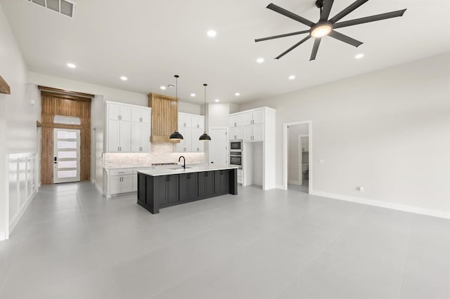 15600 Rockwell Park Ln, Edmond, OK 73013 - kitchen featuring ceiling fan, white cabinets, backsplash, a large island with sink, and recessed lighting