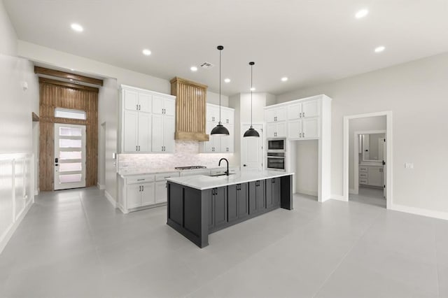 15600 Rockwell Park Ln, Edmond, OK 73013 - kitchen featuring stainless steel appliances, range hood, white cabinetry, backsplash, and a large island with sink
