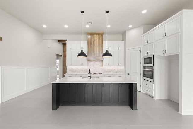 15600 Rockwell Park Ln, Edmond, OK 73013 - kitchen with stainless steel appliances, extractor fan, white cabinetry, decorative backsplash, and wainscoting