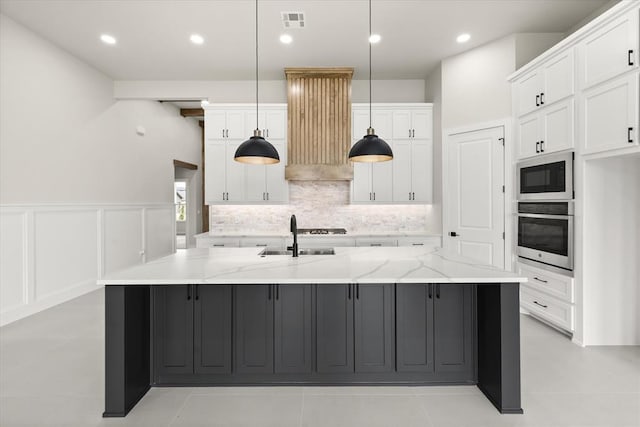 15600 Rockwell Park Ln, Edmond, OK 73013 - kitchen with appliances with stainless steel finishes, white cabinetry, ventilation hood, a large island with sink, and tasteful backsplash