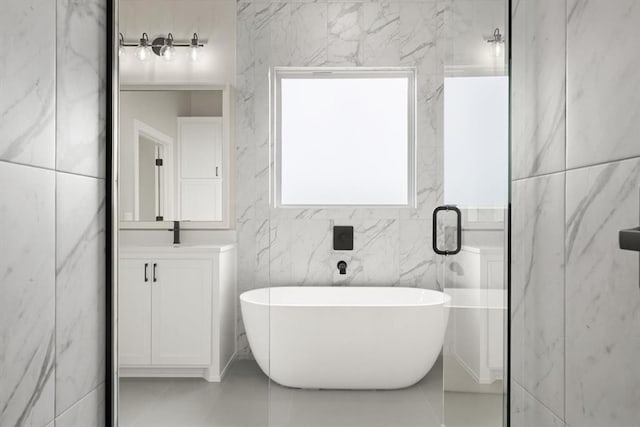 15600 Rockwell Park Ln, Edmond, OK 73013 - full bath featuring a soaking tub, vanity, tile patterned flooring, and tile walls