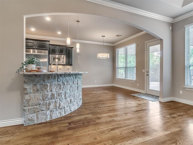 1109 Salvo Bridge Ct, Edmond, OK 73034 - bar area featuring appliances with stainless steel finishes, arched walkways, dark wood-style flooring, backsplash, and crown molding