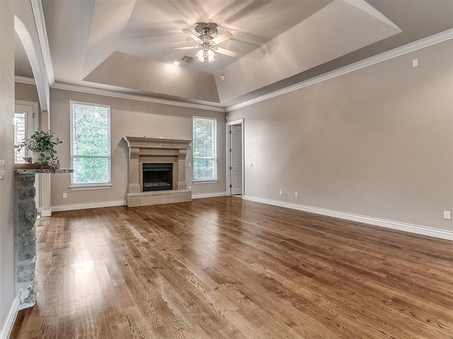 1109 Salvo Bridge Ct, Edmond, OK 73034 - unfurnished living room featuring a raised ceiling, a ceiling fan, wood finished floors, a fireplace with raised hearth, and crown molding