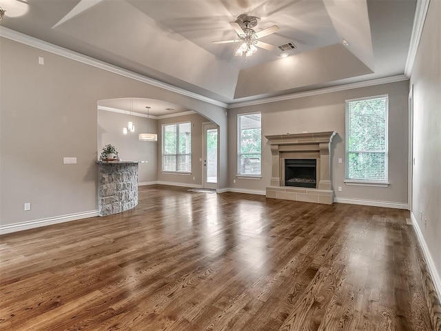 1109 Salvo Bridge Ct, Edmond, OK 73034 - unfurnished living room with a tray ceiling, arched walkways, a ceiling fan, wood finished floors, and crown molding