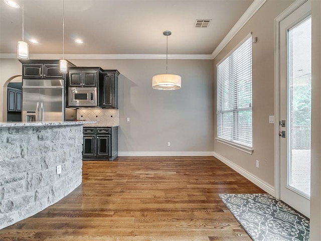 1109 Salvo Bridge Ct, Edmond, OK 73034 - kitchen with built in appliances, ornamental molding, backsplash, wood finished floors, and light stone countertops