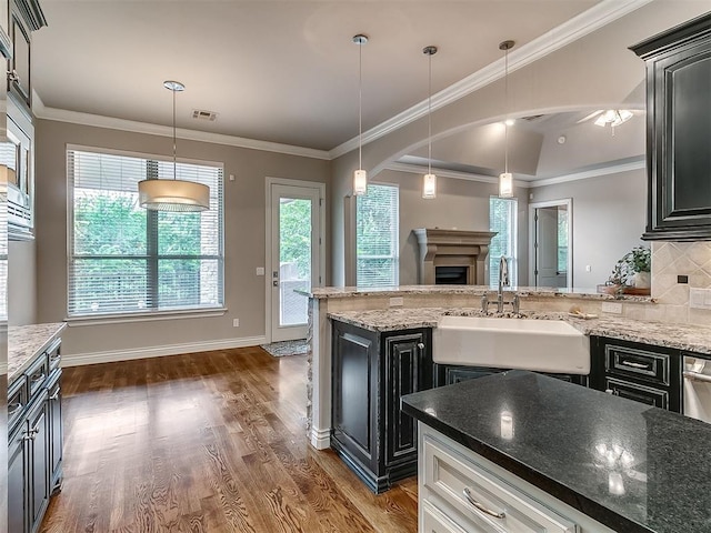 1109 Salvo Bridge Ct, Edmond, OK 73034 - kitchen featuring dark wood finished floors, backsplash, a fireplace, pendant lighting, and light stone countertops