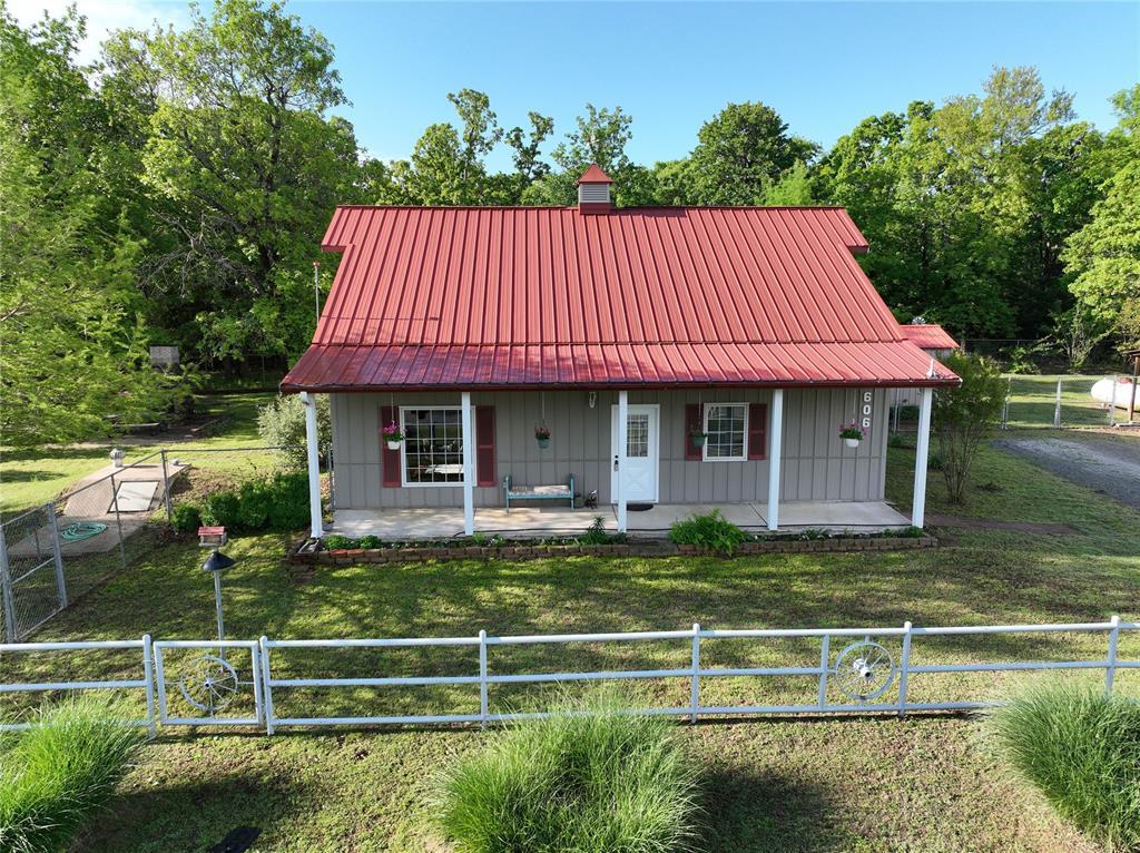 view of front of property with a front lawn, board and batten siding, a porch, fence private yard, and metal roof
