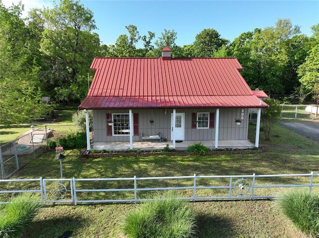 view of front of property with a front lawn, board and batten siding, a porch, fence private yard, and metal roof