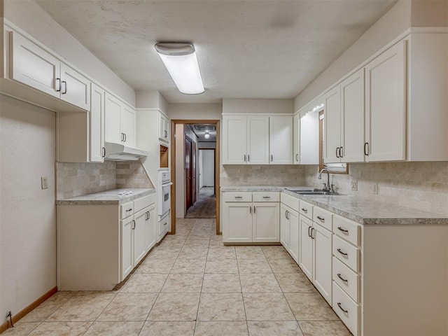 kitchen featuring light tile patterned flooring, light countertops, a sink, under cabinet range hood, and white cabinets