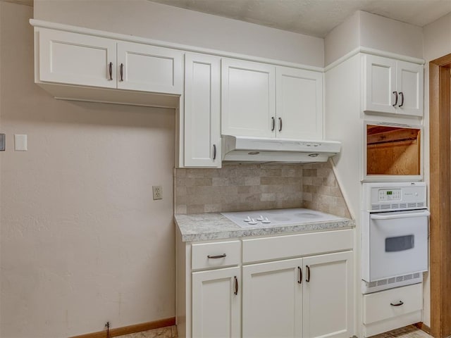 kitchen featuring light countertops, under cabinet range hood, white appliances, white cabinets, and decorative backsplash
