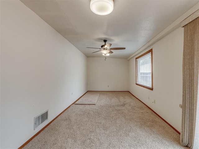empty room featuring baseboards, ceiling fan, visible vents, and light colored carpet