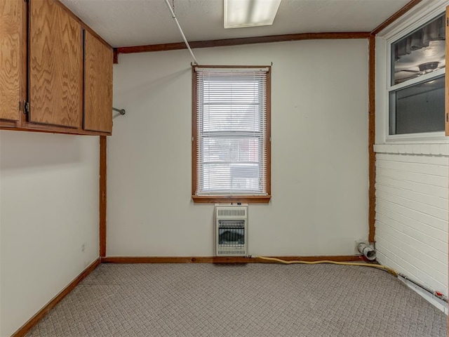 spare room featuring heating unit, light colored carpet, and baseboards