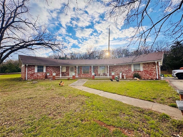 single story home with brick siding, a porch, and a front yard