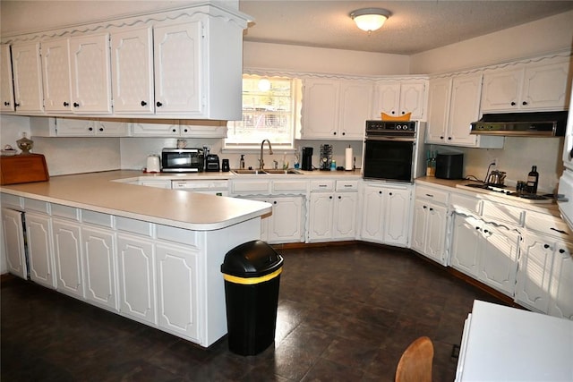 kitchen featuring white cabinets, a peninsula, white appliances, under cabinet range hood, and a sink