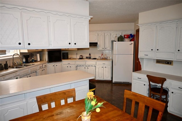 kitchen featuring a textured ceiling, white cabinets, light countertops, a sink, and freestanding refrigerator