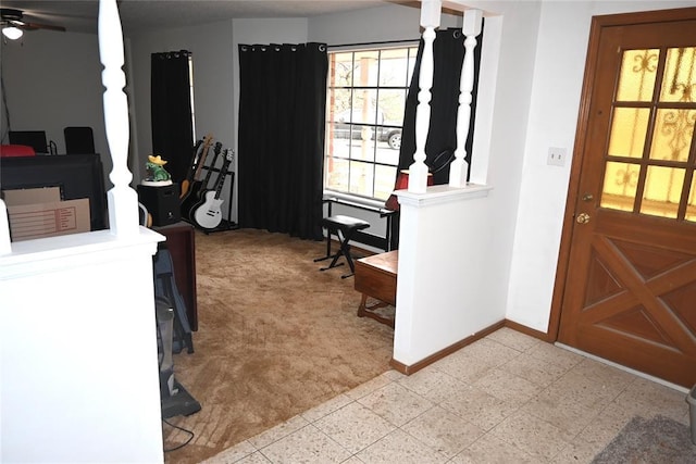 entryway featuring a ceiling fan, baseboards, and light colored carpet