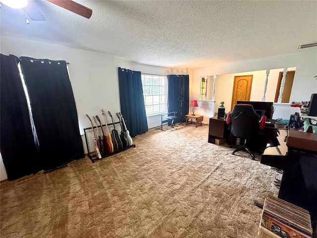 carpeted office with a textured ceiling, visible vents, and a ceiling fan