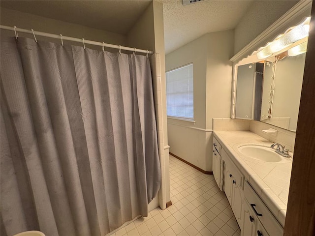 full bath featuring toilet, vanity, a textured ceiling, tile patterned flooring, and baseboards