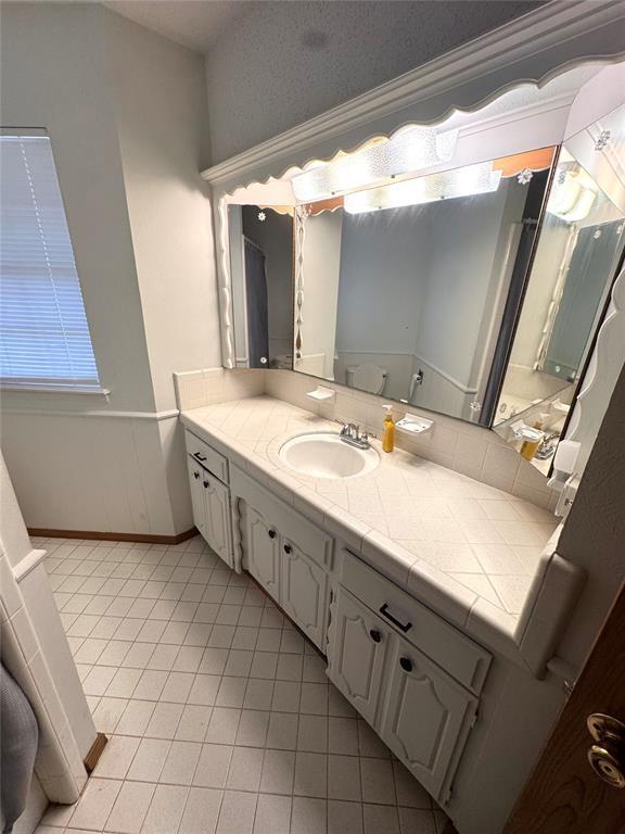 bathroom with baseboards, tile patterned flooring, and vanity