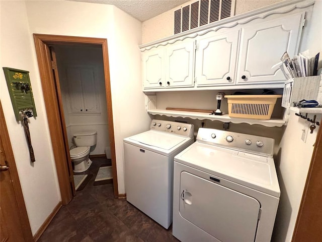clothes washing area featuring washing machine and clothes dryer, cabinet space, baseboards, and a textured ceiling