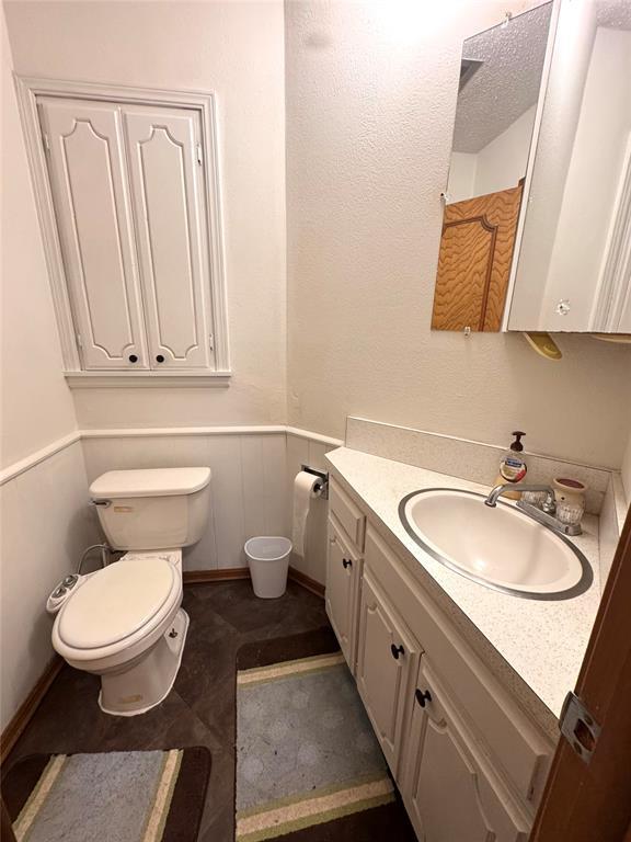 bathroom featuring a wainscoted wall, toilet, and vanity