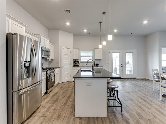 8512 NW 77th St, Oklahoma City, OK 73132 - kitchen featuring tasteful backsplash, visible vents, appliances with stainless steel finishes, a kitchen island with sink, and dark countertops