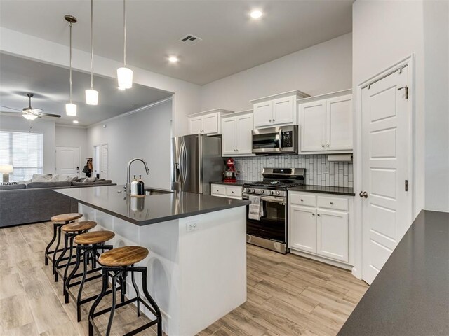 8512 NW 77th St, Oklahoma City, OK 73132 - kitchen with open floor plan, ceiling fan, dark countertops, appliances with stainless steel finishes, and a kitchen breakfast bar