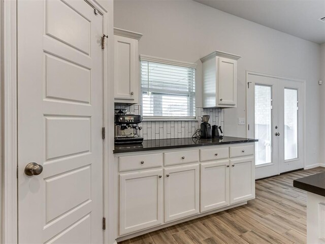 8512 NW 77th St, Oklahoma City, OK 73132 - kitchen with dark countertops, backsplash, white cabinets, and light wood finished floors