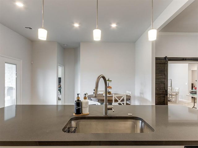8512 NW 77th St, Oklahoma City, OK 73132 - kitchen with visible vents, a barn door, a sink, dark countertops, and pendant lighting