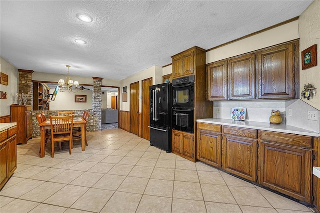 13989 US Highway 183, Hobart, OK 73651 - kitchen with black appliances, a textured ceiling, a chandelier, light countertops, and a wainscoted wall