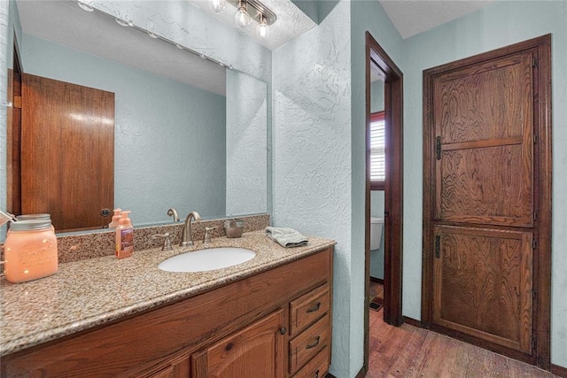 13989 US Highway 183, Hobart, OK 73651 - bathroom featuring vanity, a textured wall, wood finished floors, and toilet