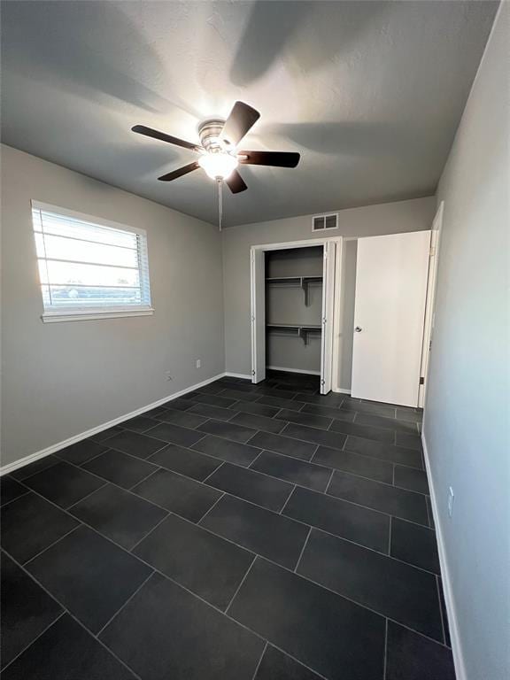 7440 NW 5th Ter, Oklahoma City, OK 73127 - unfurnished bedroom with dark tile patterned flooring, a closet, a ceiling fan, visible vents, and baseboards