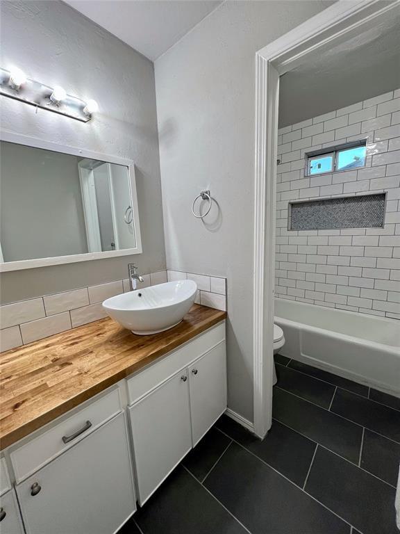 7440 NW 5th Ter, Oklahoma City, OK 73127 - bathroom featuring baseboards, shower / washtub combination, toilet, vanity, and tile patterned flooring