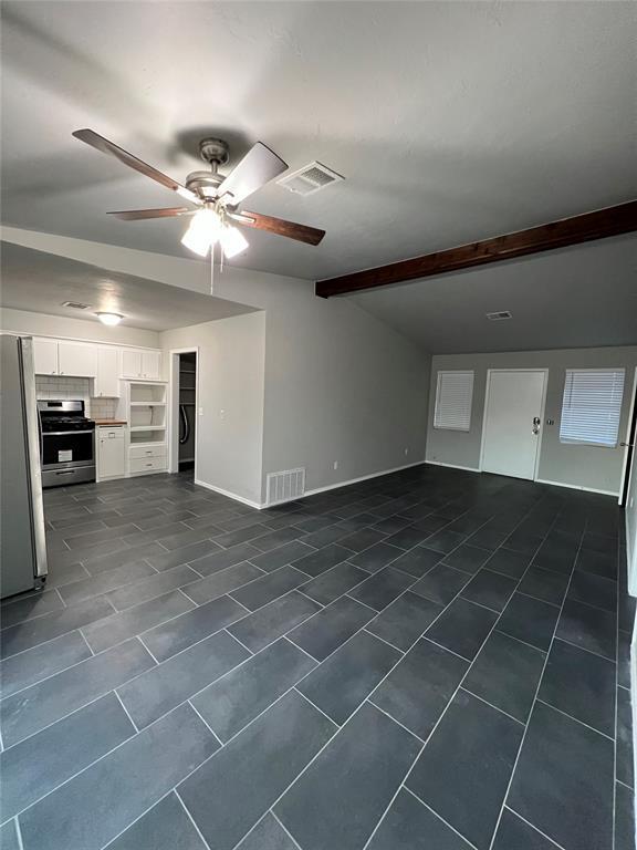 7440 NW 5th Ter, Oklahoma City, OK 73127 - unfurnished living room featuring visible vents, baseboards, a ceiling fan, and dark tile patterned flooring
