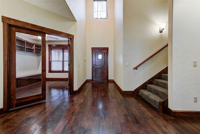 entrance foyer with baseboards, stairs, a towering ceiling, and dark wood-style flooring