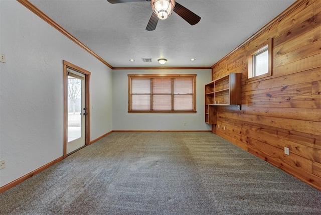 unfurnished living room featuring ornamental molding, carpet, baseboards, a textured ceiling, and visible vents