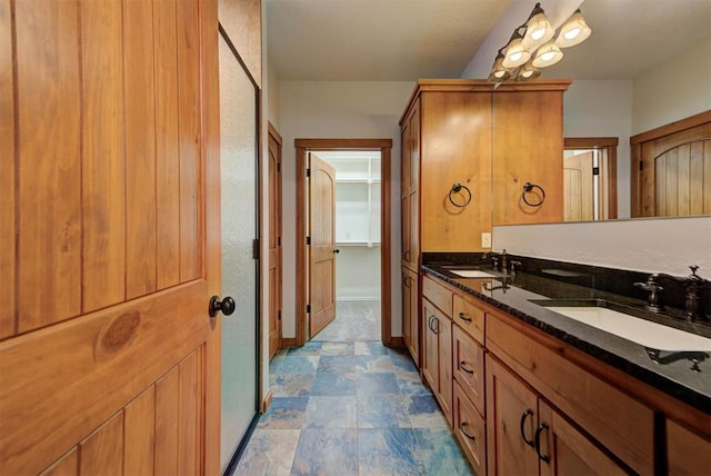 bathroom with double vanity, a sink, stone finish floor, and baseboards