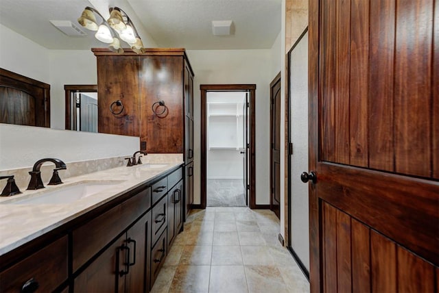 full bathroom featuring a spacious closet, double vanity, a sink, and visible vents