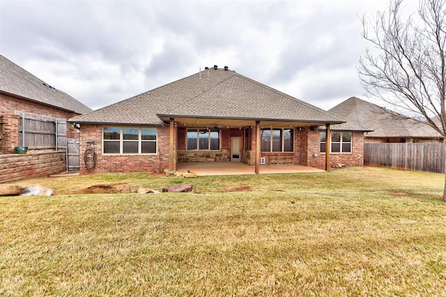 back of house with brick siding, a fenced backyard, a yard, and a patio area