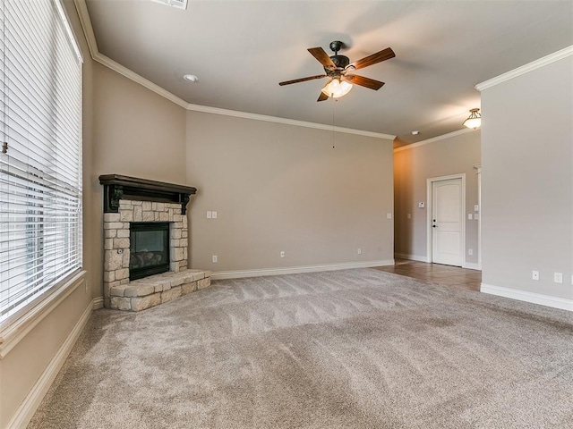 unfurnished living room featuring crown molding, carpet, baseboards, ceiling fan, and a stone fireplace