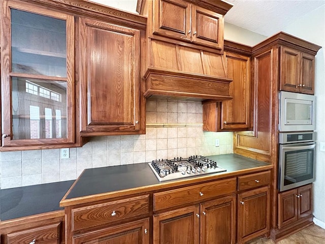 4000 Harrogate Dr, Norman, OK 73072 - kitchen featuring dark countertops, stainless steel appliances, tasteful backsplash, and brown cabinets