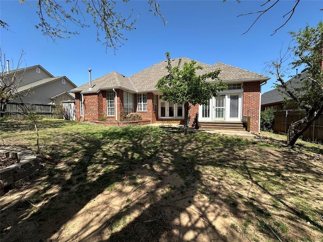 4000 Harrogate Dr, Norman, OK 73072 - rear view of property featuring entry steps, brick siding, fence private yard, a shingled roof, and a lawn