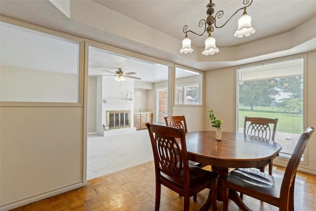 57 Serenada Ln, Shawnee, OK 74804 - dining space with ceiling fan, a fireplace, a chandelier, baseboards, and light carpet