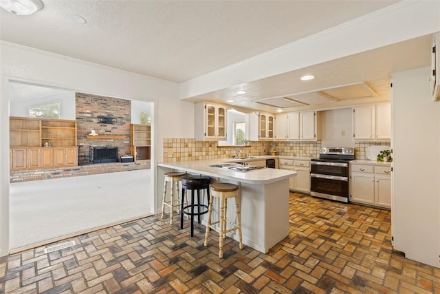 57 Serenada Ln, Shawnee, OK 74804 - kitchen with appliances with stainless steel finishes, a peninsula, decorative backsplash, glass insert cabinets, and recessed lighting