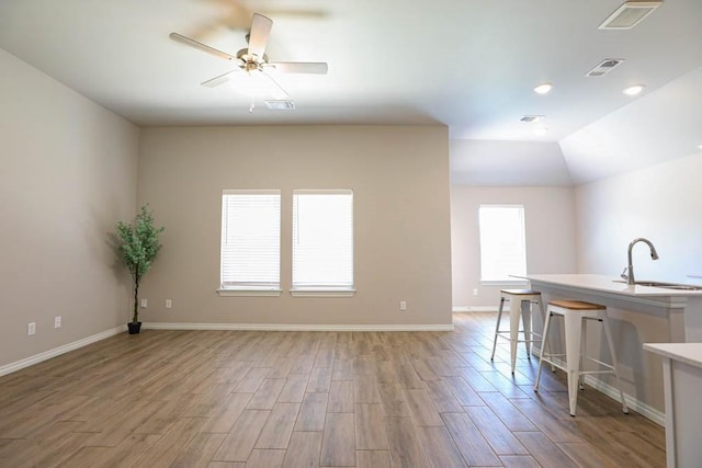 interior space with light wood-style flooring, visible vents, a sink, and ceiling fan
