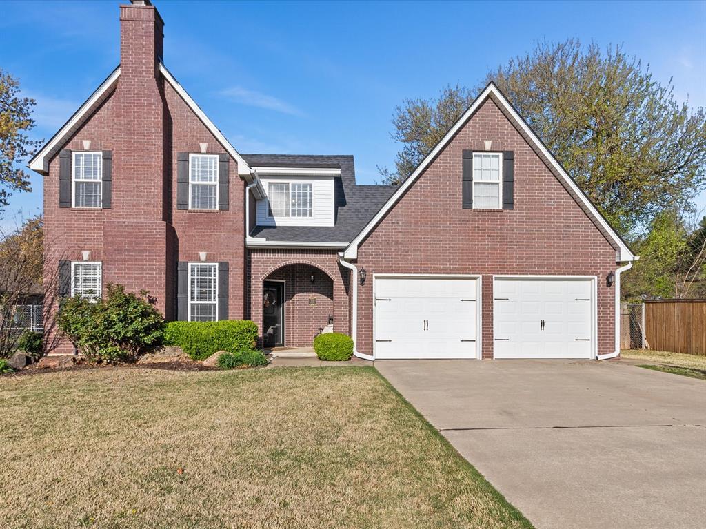 view of front of property with a chimney, driveway, an attached garage, a front lawn, and fence