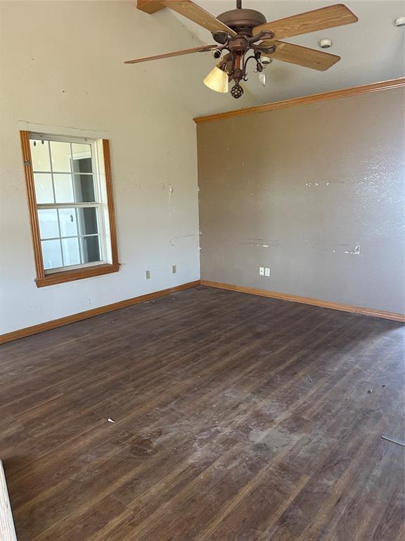 empty room with baseboards, wood finished floors, and a ceiling fan